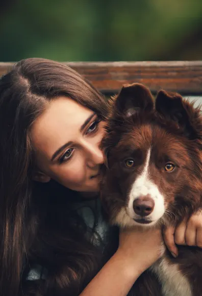 Woman hugging dog in front of gate